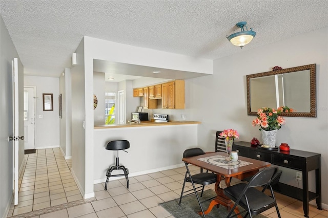 dining room featuring light tile patterned floors, a textured ceiling, and baseboards