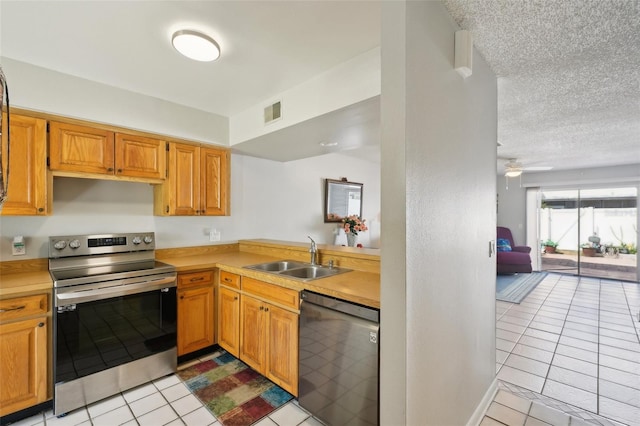 kitchen featuring stainless steel appliances, light countertops, a sink, and a textured ceiling