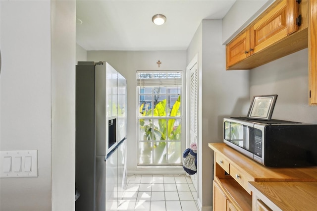 interior space featuring appliances with stainless steel finishes, brown cabinets, and light tile patterned floors