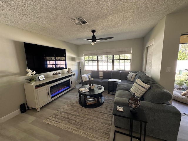 living area with visible vents, baseboards, ceiling fan, a textured ceiling, and light wood-style floors