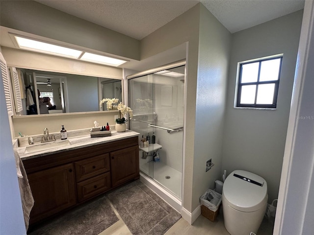 bathroom with a stall shower, vanity, toilet, and a skylight