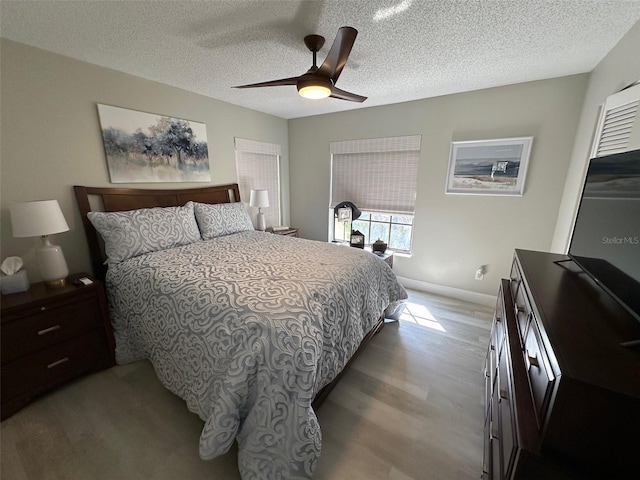 bedroom featuring a textured ceiling, wood finished floors, a ceiling fan, and baseboards