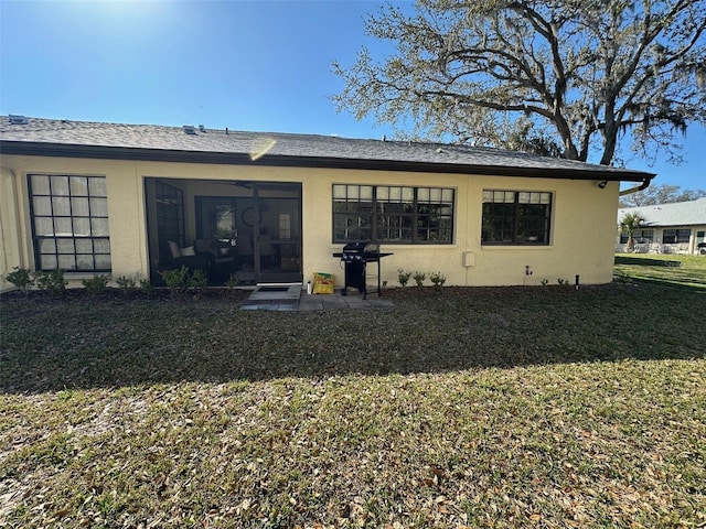 rear view of property with a lawn, a sunroom, and stucco siding