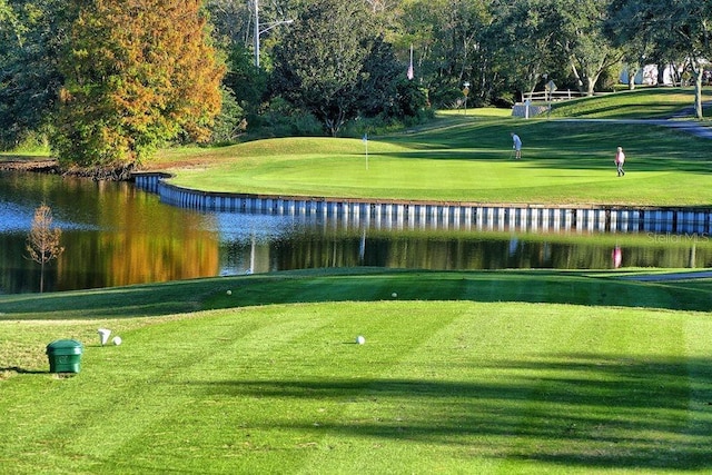 view of community with view of golf course, a water view, and a lawn