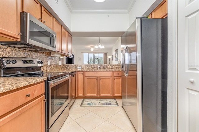 kitchen with appliances with stainless steel finishes, ornamental molding, a sink, a notable chandelier, and light tile patterned flooring