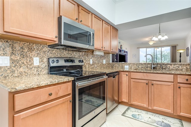 kitchen with appliances with stainless steel finishes, a sink, light stone counters, and tasteful backsplash