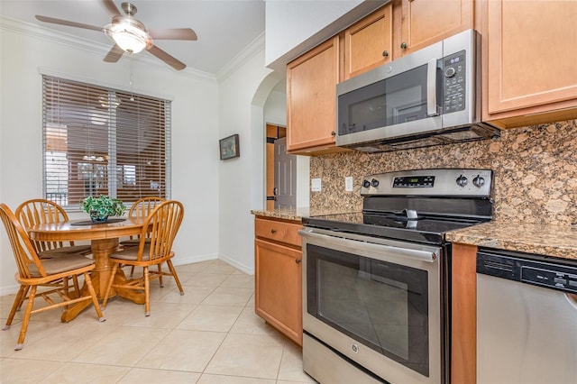 kitchen featuring arched walkways, crown molding, light tile patterned floors, decorative backsplash, and appliances with stainless steel finishes