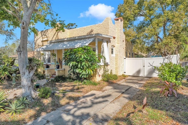 view of side of home featuring a gate, fence, and stucco siding