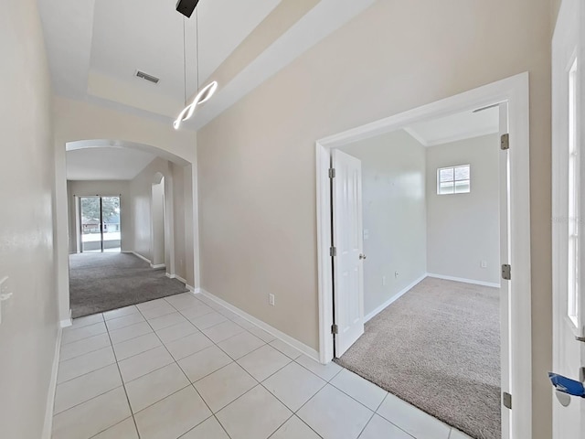 hallway featuring arched walkways, light carpet, visible vents, and light tile patterned flooring