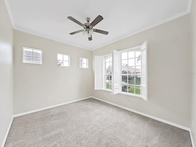 spare room with a ceiling fan, carpet flooring, crown molding, and baseboards