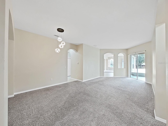 spare room with carpet floors, arched walkways, visible vents, and baseboards