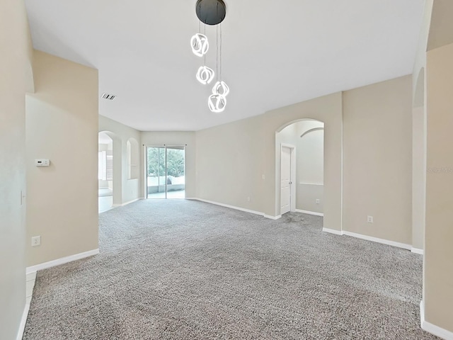 carpeted spare room featuring arched walkways, visible vents, and baseboards