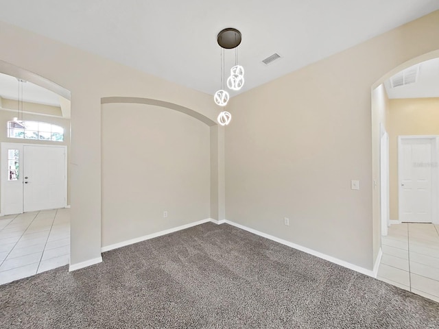 unfurnished room featuring carpet floors, visible vents, and tile patterned floors