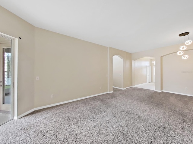 unfurnished room with arched walkways, carpet flooring, and baseboards