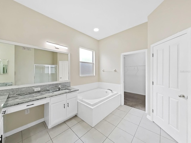 bathroom featuring a garden tub, tile patterned flooring, vanity, a shower stall, and a walk in closet