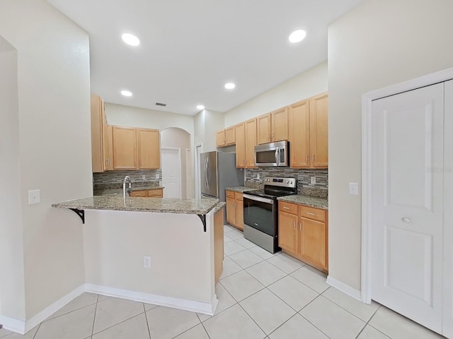 kitchen with stainless steel appliances, arched walkways, a peninsula, and a kitchen breakfast bar