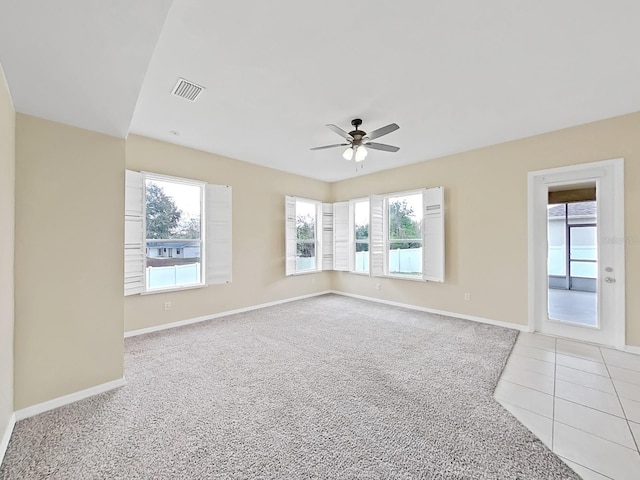 unfurnished room with light tile patterned floors, visible vents, light carpet, ceiling fan, and baseboards