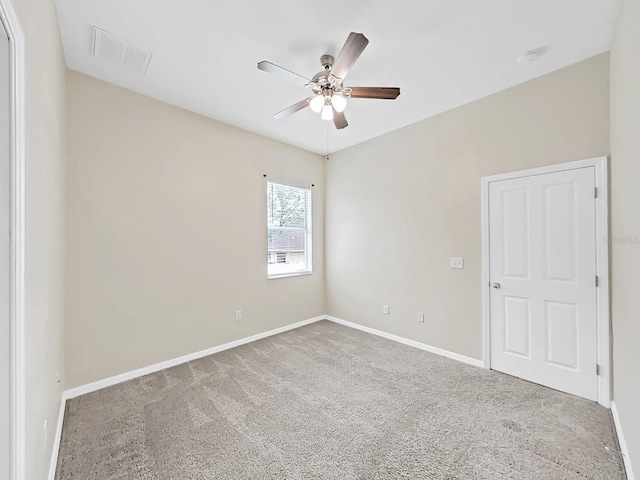 spare room featuring carpet flooring, ceiling fan, visible vents, and baseboards