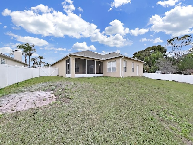 rear view of property featuring a yard, a fenced backyard, a sunroom, and stucco siding