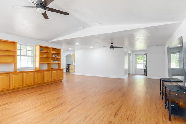 living room with arched walkways, a ceiling fan, baseboards, vaulted ceiling, and light wood-style floors