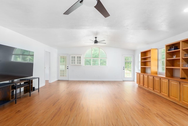 living room featuring lofted ceiling, light wood-type flooring, and baseboards