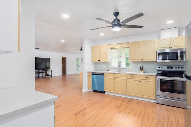 kitchen with light countertops, appliances with stainless steel finishes, a sink, and light wood-style floors