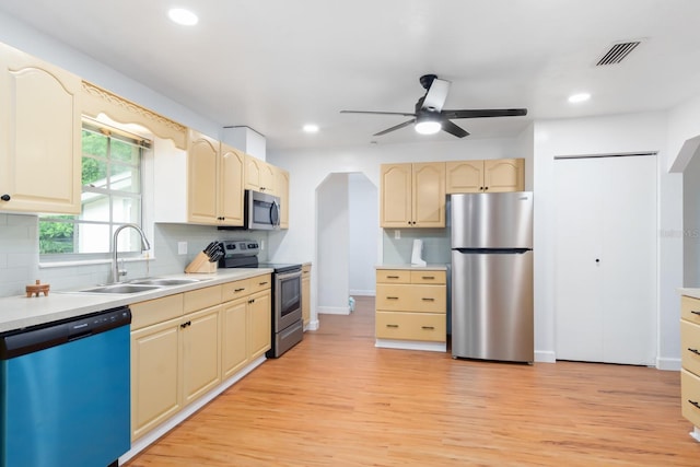 kitchen with a sink, visible vents, appliances with stainless steel finishes, light wood-type flooring, and backsplash