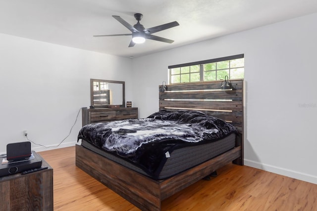 bedroom featuring ceiling fan, baseboards, and wood finished floors