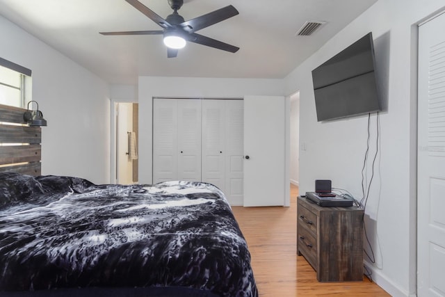 bedroom with light wood finished floors, ceiling fan, visible vents, and a closet