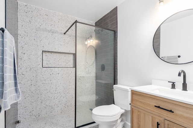 bathroom with toilet, a shower stall, and vanity