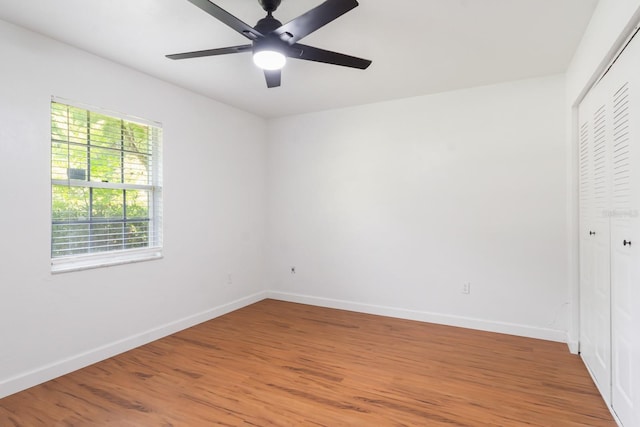 unfurnished bedroom featuring a ceiling fan, light wood-style flooring, baseboards, and a closet