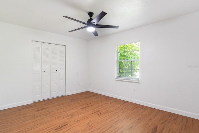 unfurnished bedroom featuring ceiling fan, light wood finished floors, a closet, and baseboards