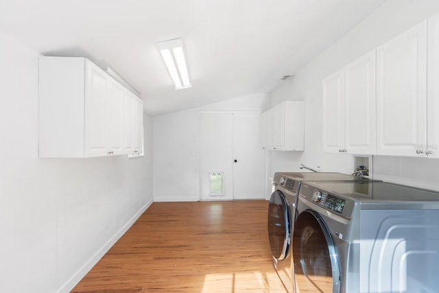 laundry area featuring baseboards, cabinet space, light wood finished floors, and washing machine and clothes dryer