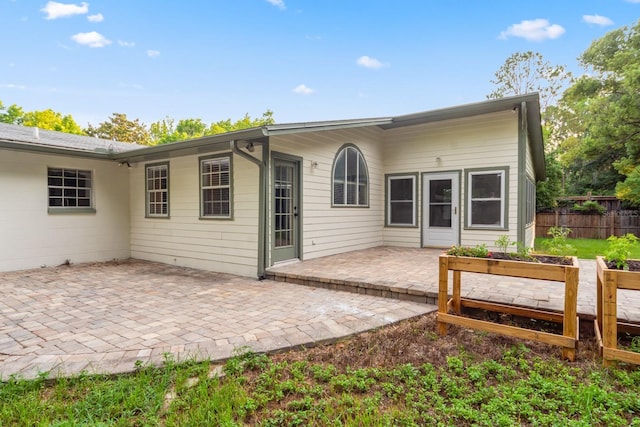 rear view of property featuring a patio area, a garden, and fence