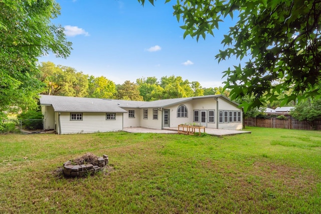 rear view of property with a yard, fence, a fire pit, and a patio