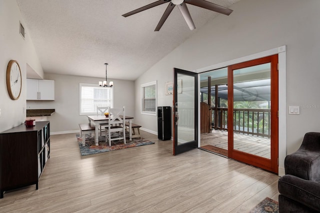 dining area featuring light wood-style floors, visible vents, vaulted ceiling, and a textured ceiling