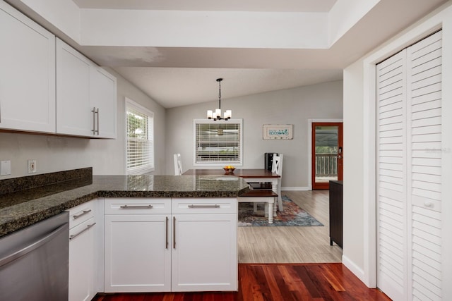 kitchen with a peninsula, dark wood-type flooring, white cabinets, dishwasher, and an inviting chandelier