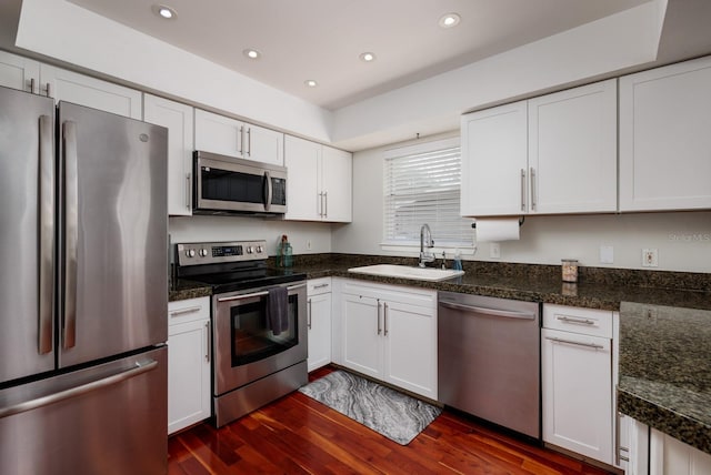 kitchen featuring appliances with stainless steel finishes, dark wood finished floors, white cabinets, and a sink