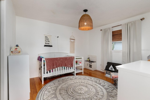 bedroom featuring a nursery area and wood finished floors