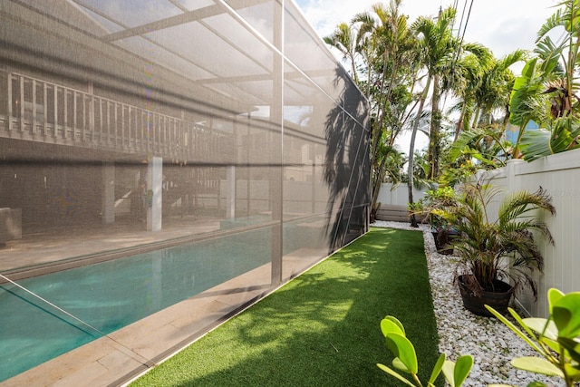 view of pool with a lanai, a fenced backyard, and a lawn