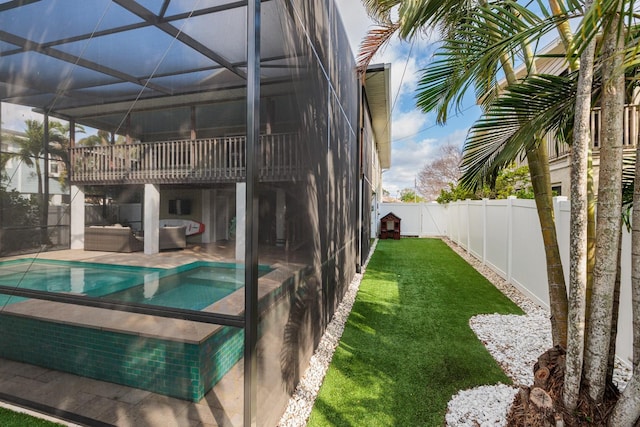 view of pool with a patio, glass enclosure, a fenced backyard, a yard, and a fenced in pool