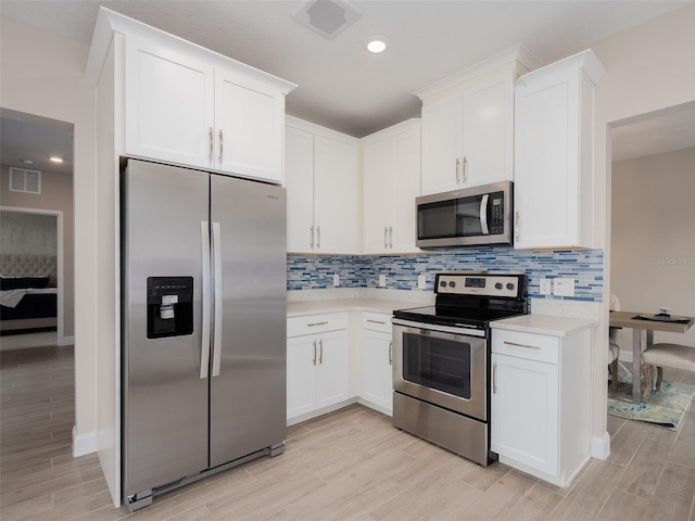 kitchen featuring stainless steel appliances, backsplash, light countertops, and wood tiled floor