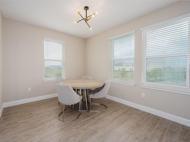 dining room with light wood-style flooring, baseboards, and an inviting chandelier