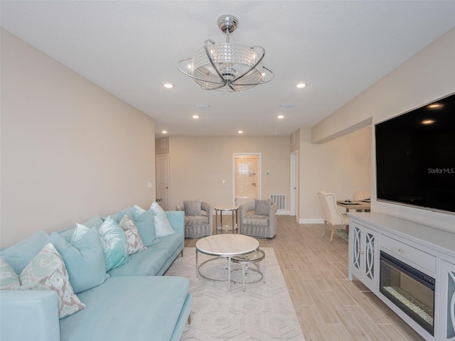 living room featuring visible vents, baseboards, light wood-style flooring, an inviting chandelier, and recessed lighting