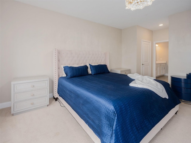 carpeted bedroom with connected bathroom, baseboards, and an inviting chandelier