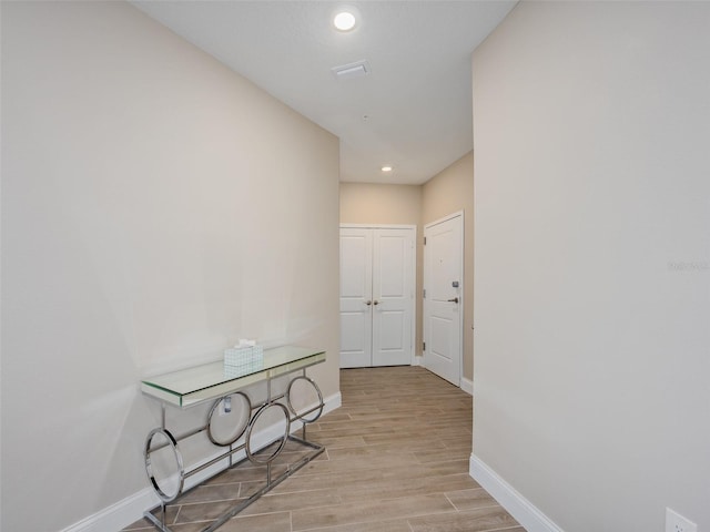 corridor with baseboards, recessed lighting, and light wood-style floors