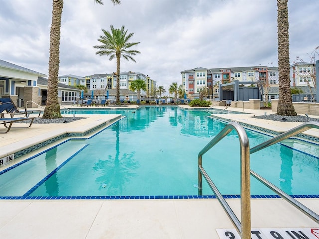 community pool featuring a patio, fence, and a residential view