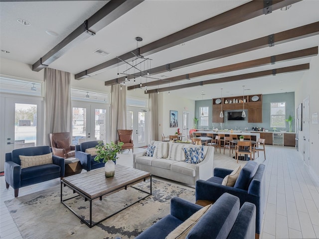 living area with visible vents, baseboards, french doors, beam ceiling, and light wood finished floors