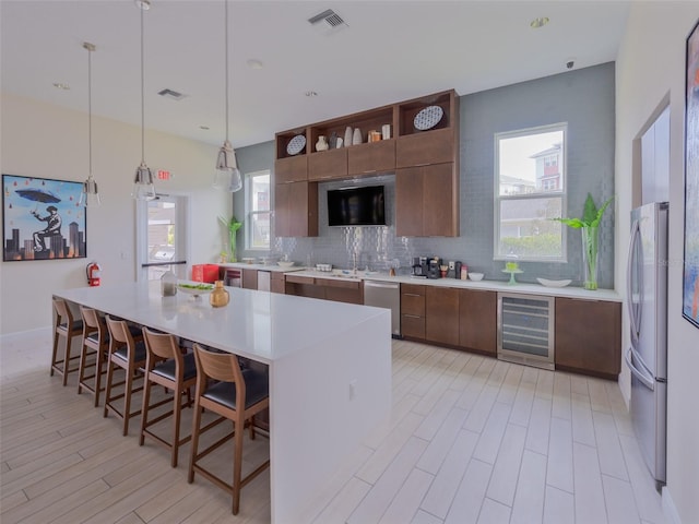 kitchen with tasteful backsplash, beverage cooler, visible vents, stainless steel appliances, and light countertops