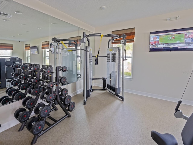 workout area featuring baseboards, visible vents, and a textured ceiling